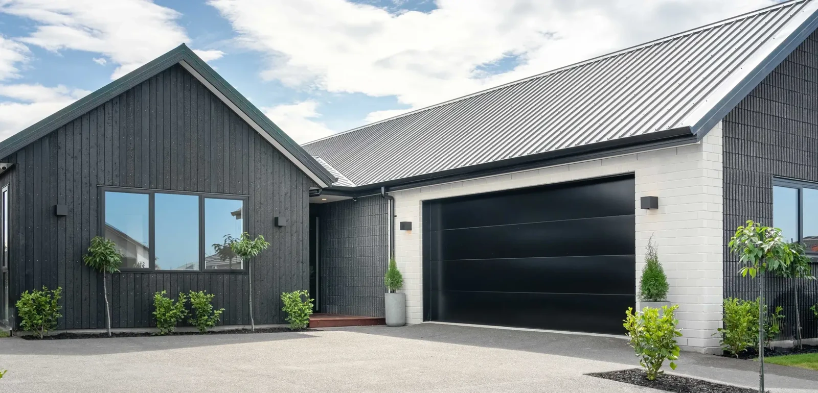 Modern single-story home with a black wooden exterior and garage door | Classic Builders