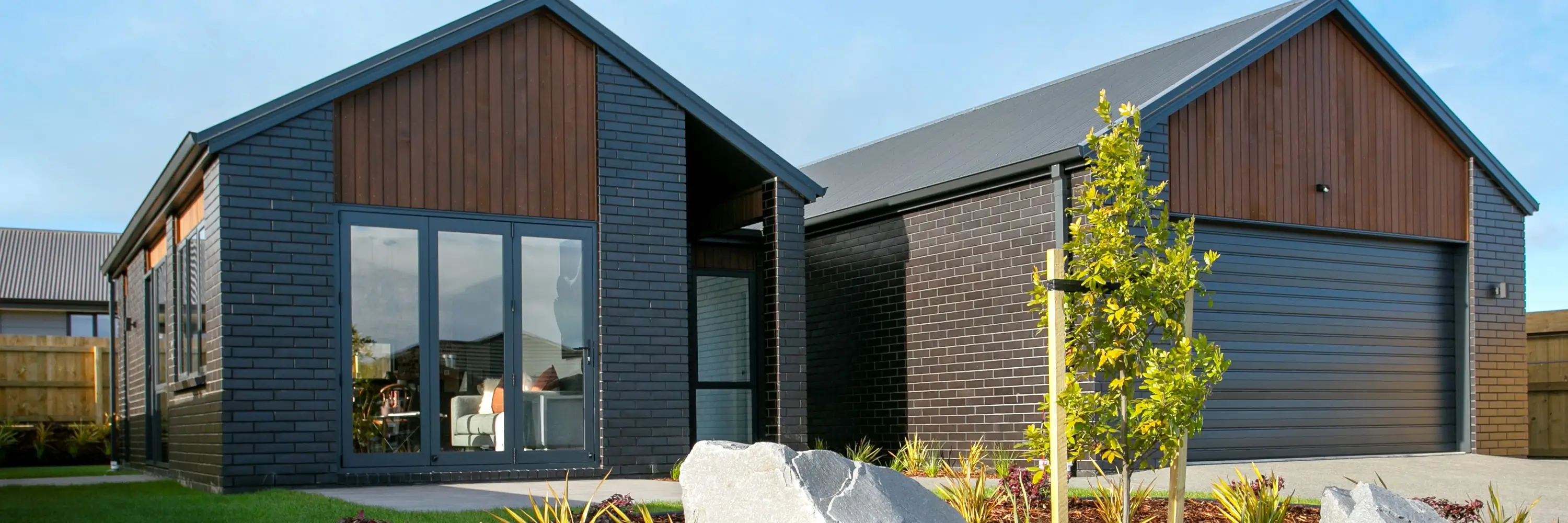 Modern home with dark brick, wood paneling, and an attached garage | Classic Builders