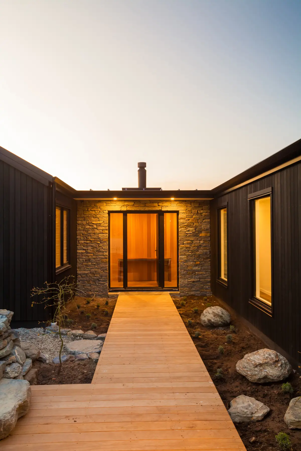 Timber walkway leading to the stone-clad entrance of a Classic Builders Queenstown show home