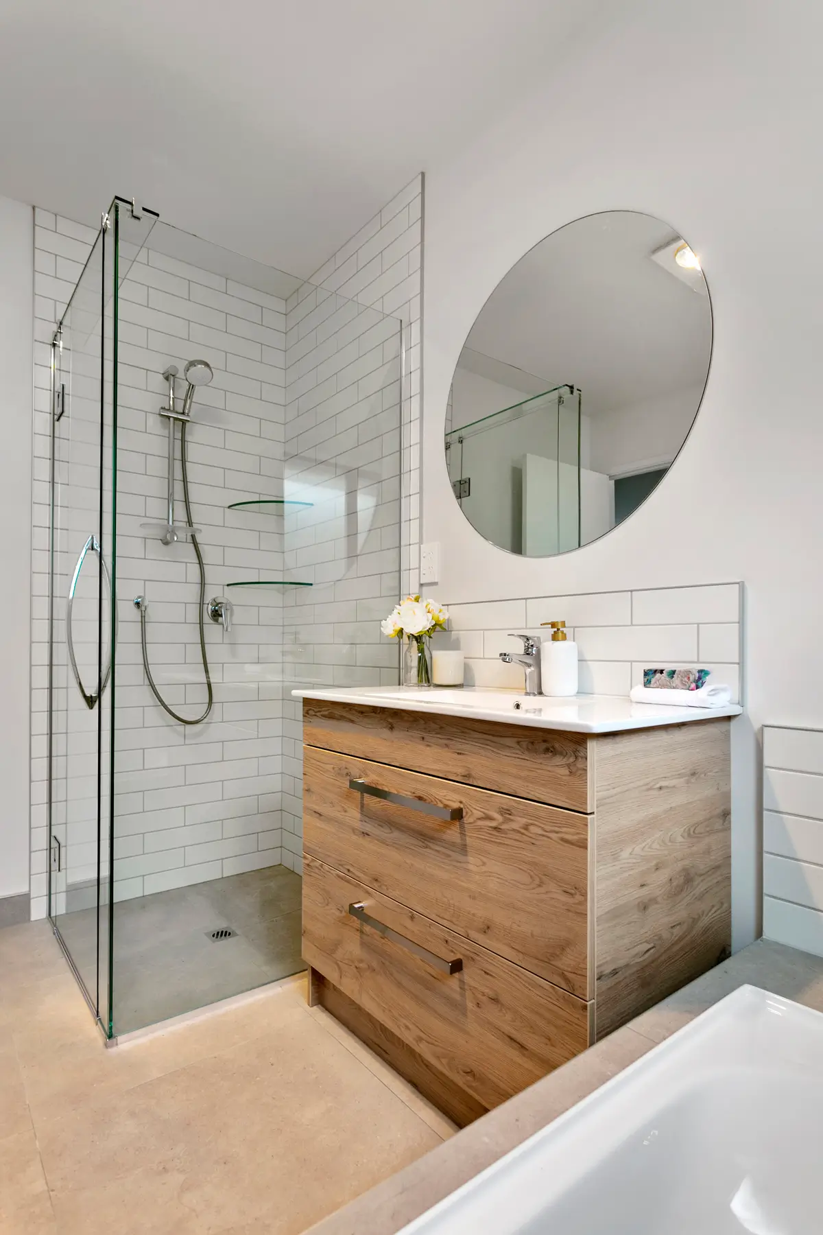 Modern bathroom design with glass shower, timber vanity and round mirror