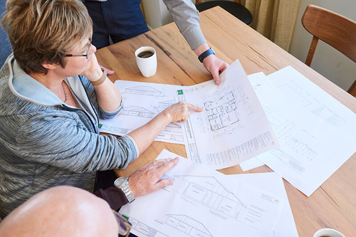 People around table examining house floor plans.