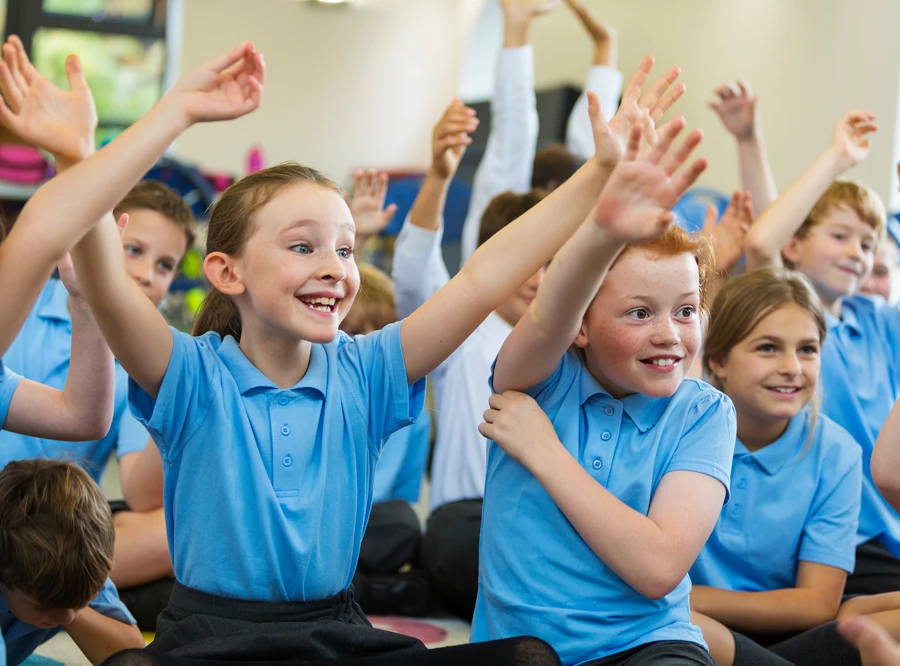 Kids in school raising their hands.